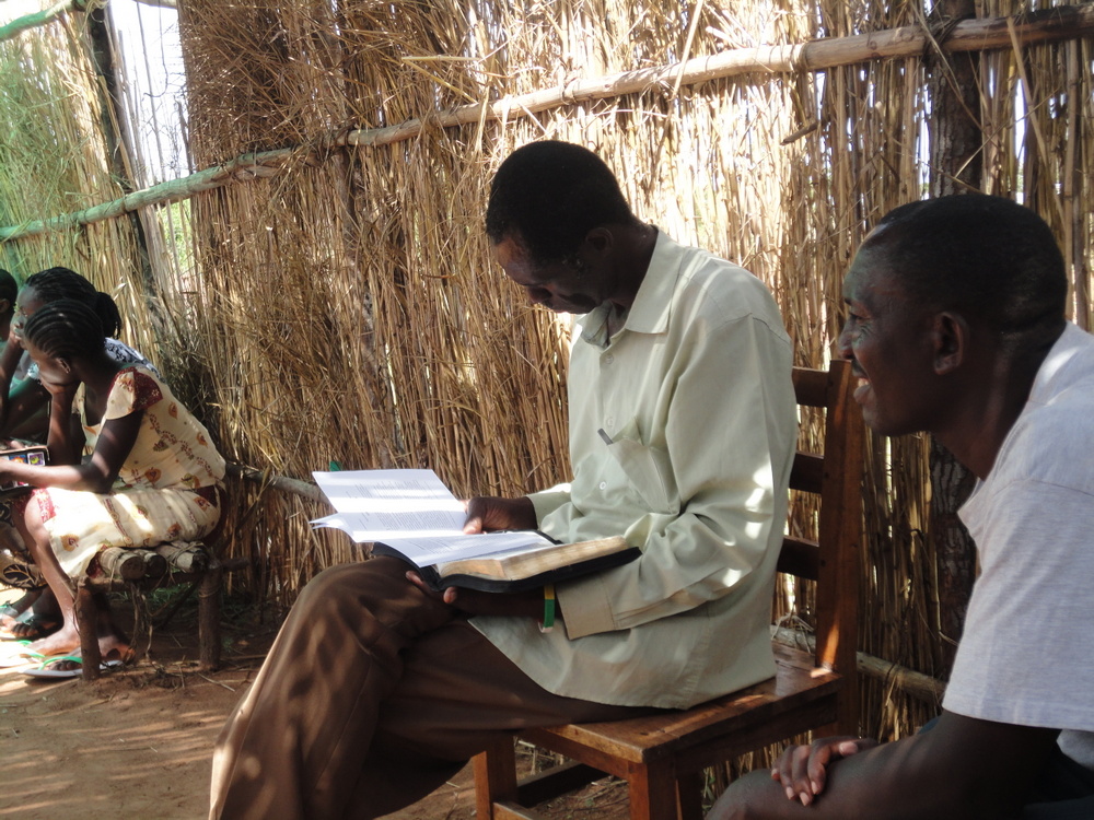 Terwijl onze vertalers voorleest, leest deze man mee in zijn boekje met de twee brieven van Paulus aan de Thessalonisenzen