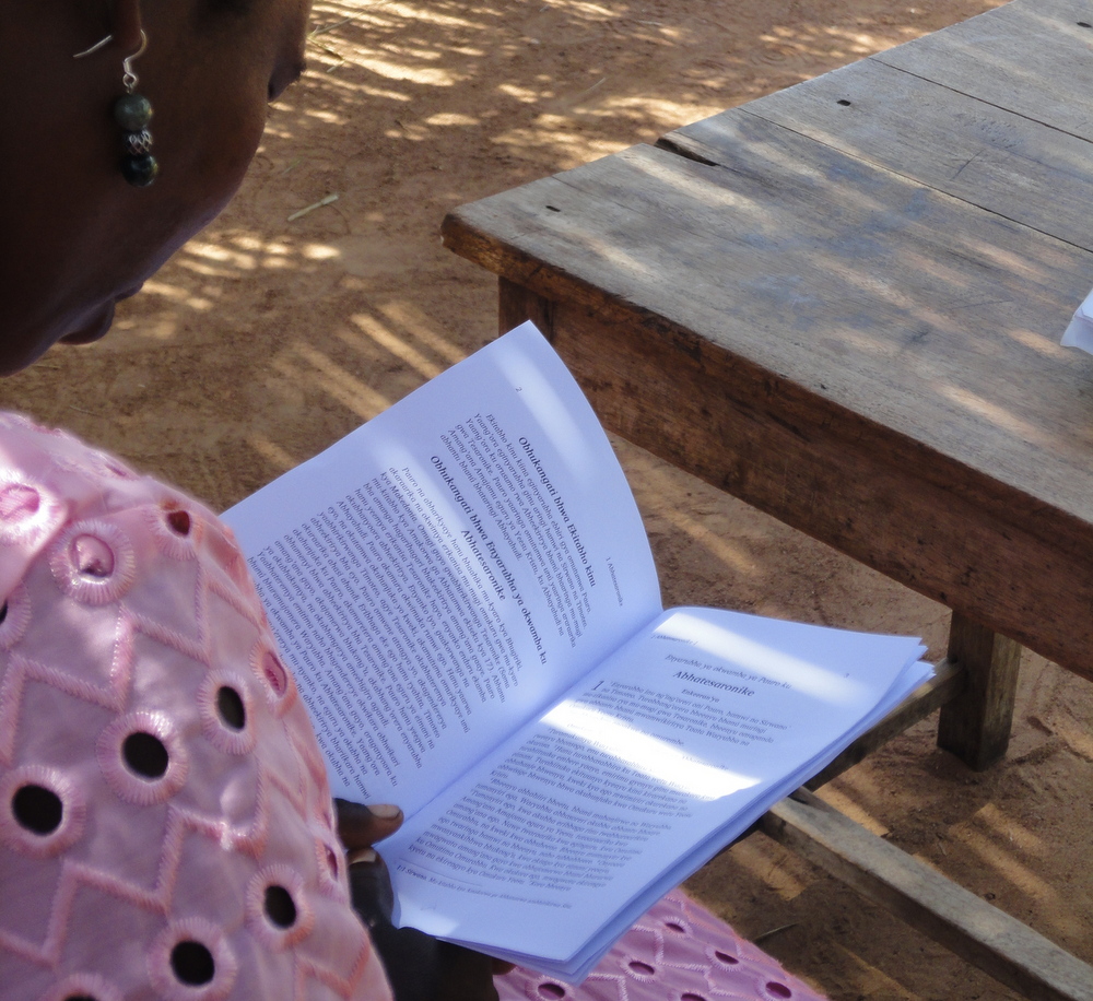 Vrouw leest mee in haar boekje met de Thessalonisenzen-brieven in de Kabwa-taal.